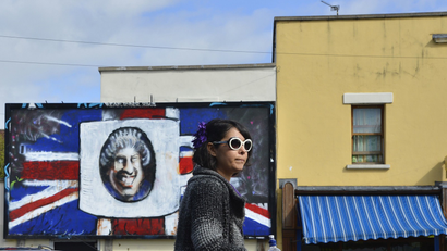 A pedestrian passes street art depicting Britain's Queen Elizabeth.