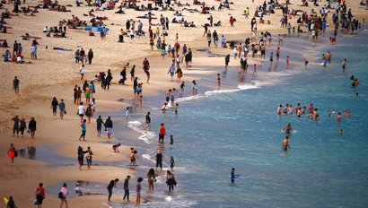 Beachgoers swim and stand on the edge of the water at Sydney's Bondi Beach on a winter day in Australia