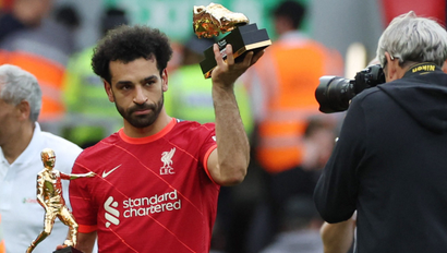 Mohamed Salah of Liverpool raises his award for being the top scorer in the English Premier League on one hand, with another award for providing the most assists on another hand.