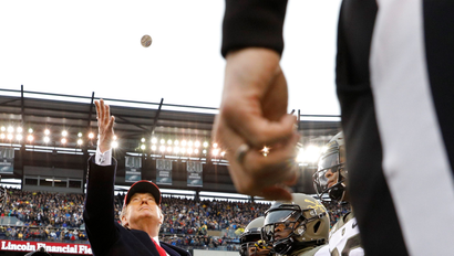 President Trump tosses a coin at the start of a football game.