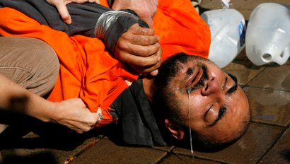 Demonstrator Maboud Ebrahimzadeh lies on the pavement after his ordeal in a simulation of waterboarding outside the Justice Department in Washington November 5, 2007. The confirmation of Bush nominee Michael Mukasey as attorney general is in jeopardy after his refusal to state whether the interrogation technique known as waterboarding violates U.S. laws banning torture. REUTERS/Kevin Lamarque (UNITED STATES) - RTR1VOW6