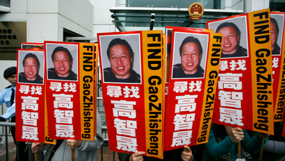 A policeman stands guard as protesters carrying portraits of one of China's most prominent dissidents, Gao Zhisheng, demonstrate outside a Chinese liaison office in Hong Kong February 4, 2010. Gao, an outspoken lawyer who took on sensitive cases that riled China's ruling Communist Party, has been missing for one year. Chinese characters read "Look for Gao Zhisheng".