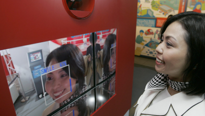 A woman smiles as she demonstrates Japanese electronics and health-care company Omron Corp.'s Okao Catch, or "face catch," that can measure how big your smile is during a newly opened technology exhibition space TEPIA in Tokyo Thursday, April 10, 2008. The software technology scans a video image to detect faces. It can find up to 100 faces in an image, according to Yasushi Kawamoto of Omron. Okao Catch then analyzes curves of the lips, eye movements and other facial expressions to decide how much a person is smiling using data collected from a million people and their smiles, he said.