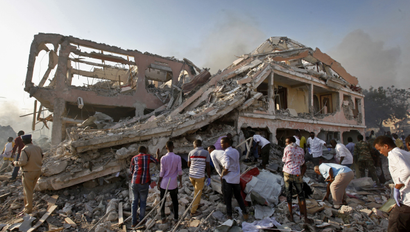 Somalis gather and search for survivors by destroyed buildings at the scene of a blast in the capital Mogadishu, Somalia Saturday, Oct. 14, 2017. A huge explosion from a truck bomb has killed at least 20 people in Somalia's capital, police said Saturday, as shaken residents called it the most powerful blast they'd heard in years.