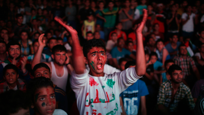 Palestinians cheer as they watch the soccer match between their national team and Philippines on large screens during the AFC Cup Final, in Gaza City May 30, 2014,