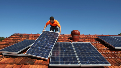Solar system installer Bywater adjusts new solar panels on the roof of a house in Sydney