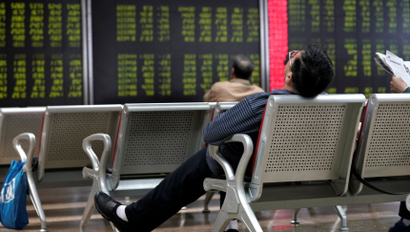 An investor takes a nap in front of a board showing stock information at a brokerage office in Beijing, China October 8, 2018. REUTERS/Jason Lee - RC1FB72E4E50