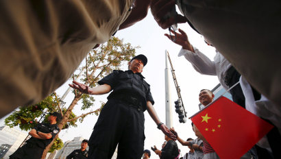 A man holding a Chinese flag and bystanders talk to a policeman blocking the area around the China Securities Regulatory Commission, during a protest against the Fanya Mental Exchange in Beijing September 21, 2015. Hundreds of investors gathered outside the headquarters of China's securities watchdog on Monday to protest against a metals exchange in a southwest province they accuse of defrauding them of billions of yuan.