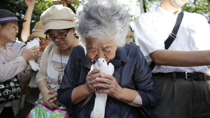 A woman, who lost her father in World War Two, holds a dove before releasing it as she prays for the war dead at the Yasukuni Shrine in Tokyo.