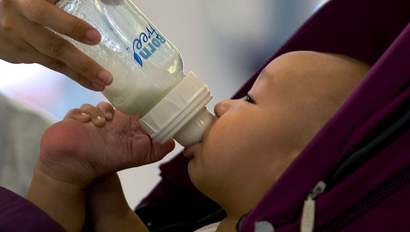 A baby is fed a milk with a nursing bottle on a stroller at a shopping mall in Beijing, China, Wednesday, Aug. 7, 2013. China announced Wednesday it has fined six milk suppliers, including Mead Johnson and New Zealand's Fonterra, a total of $108 million for price-fixing after an investigation that shook the country's fast-growing dairy market. (AP Photo/Andy Wong)