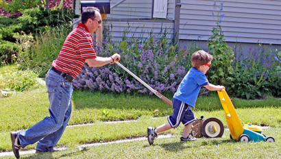 Logan Mack, right, races his father George with a toy lawnmower as the two manicure the family’s front lawn Tuesday Aug. 4, 2009 in Laramie, Wyo. (AP Photo/Laramie Boomerang, Andy Carpenean