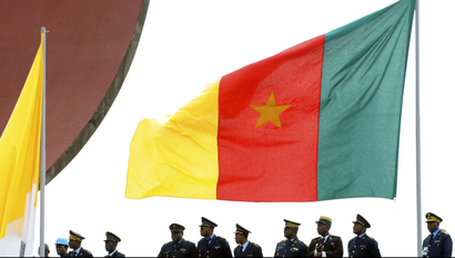 Cameroonian police stand near a national flag during a mass led by Pope Benedict XVI at Amadou Ahidjo stadium in Yaounde