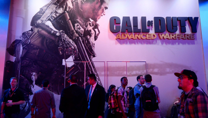 Attendees walk pass a giant billboard promoting the new multiplayer action game "Call of Duty: Advanced Warfare" at the Activision booth during the 2014 Electronic Entertainment Expo,