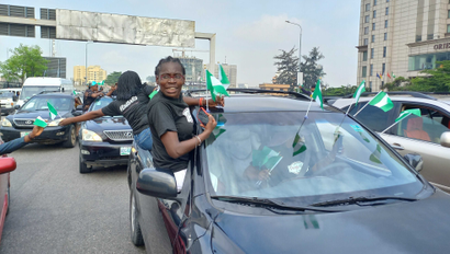 Female protesters in Nigeria hanging from a vehicle with their green and white flags in their hands during the EndSARS memorial in Lagos Nigeria