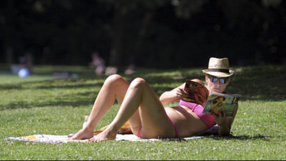 A woman reads a magazine at a central park on a warm day in Brussels.