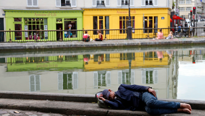 A man sleeps along the Canal Saint Martin during a hot summer day in Paris July 16, 2014. REUTERS/Charles Platiau (FRANCE - Tags: SOCIETY TRAVEL ENVIRONMENT TPX IMAGES OF THE DAY) - RTR3YWGD