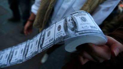 A demonstrator holds toilet paper made from fake U.S. dollars during a protest against Turkey's Prime Minister Tayyip Erdogan and his ruling Ak Party (AKP) government in Ankara February 27, 2014. An audio recording purporting to be of Erdogan giving his son business advice has been published on YouTube, following one earlier in the week that fuelled a corruption scandal and unnerved markets. Erdogan said a similar post on the video-sharing site YouTube on Monday, allegedly of him telling his son Bilal to dispose of large sums of cash as a graft investigation erupted, had been faked by his political enemies. REUTERS/Umit Bektas (TURKEY - Tags: POLITICS CIVIL UNREST CRIME LAW) - RTR3FSFR