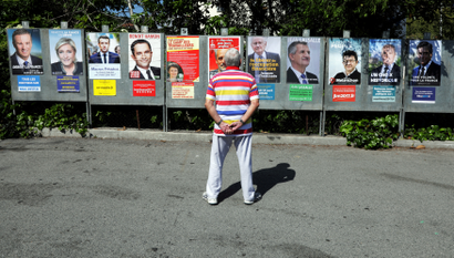 A man looks at campaign posters of the 11th candidates who are running in the 2017 French presidential election, in Saint Andre de La Roche