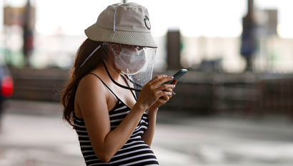 A pregnant woman wears a protective face mask and looks at her phone