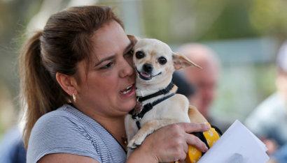 A pet owner holds her dog, talking to it