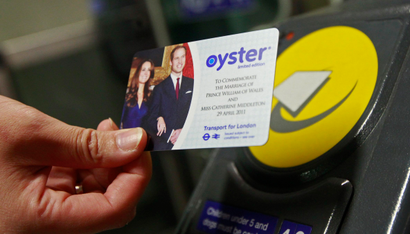 A tube passenger holds a royal wedding commemorative Oyster card, bearing an image of Britain's Prince William and his fiancee Kate Middleton, at an entrance barrier in King's Cross station in London April 21, 2011. 750,000 of the cards which are a commemorative version of the widely used electronic device used to pay for train and bus tickets in London, went on sale on Thursday. REUTERS/Luke MacGregor (BRITAIN - Tags: ENTERTAINMENT TRAVEL ROYALS SOCIETY) - RTR2LH1X