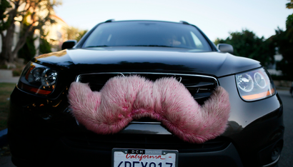 A driver with the ride-sharing service Lyft waits for a customer on a street in Santa Monica, California October 17, 2013. Lyft allows customers to book rides from a network of screened drivers, who pull up in cars with fluffy pink moustaches attached to the fenders. Payment is in the form of a donation, made via the Lyft smartphone app. REUTERS/Lucy Nicholson (UNITED STATES - Tags: BUSINESS TRANSPORT) - RTR4GW09