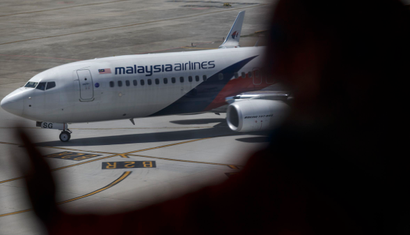 A woman looks at a Malaysia Airline aircraft sitting on the tarmac at a viewing gallery in Kuala Lumpur International Airport in Sepang July 19, 2014. U.S. President Barack Obama said the downing of a Malaysian jetliner in a Ukrainian region controlled by Russian-backed separatists should be a "wake-up call for Europe and the world" in a crisis that appears to be at a turning point and warned Russia of possible tightening of sanctions. While stopping short of blaming Russia for Thursday's crash of Malaysia Airlines Flight MH17, in which 298 people died, Obama accused Moscow of failing to stop the violence that made it possible to shoot down the plane. REUTERS/Athit Perawongmetha (MALAYSIA - Tags: TRANSPORT DISASTER) - RTR3ZAXZ