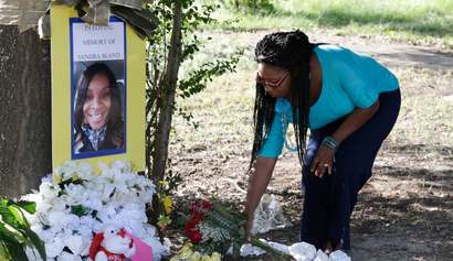 A woman puts flowers in memory of Sandra Bland