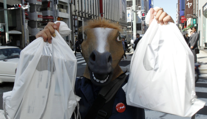 A man wearing a horse mask poses with his iPads after he bought them at an Apple store in Tokyo May 28, 2010.