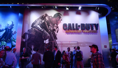 Attendees walk pass a giant billboard promoting the new multiplayer action game "Call of Duty: Advanced Warfare"