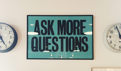 Sign reading "ASK MORE QUESTIONS"
