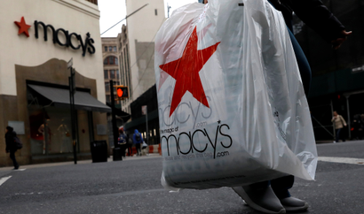 A customer carries a Macy's bag after exiting a Macy's store
