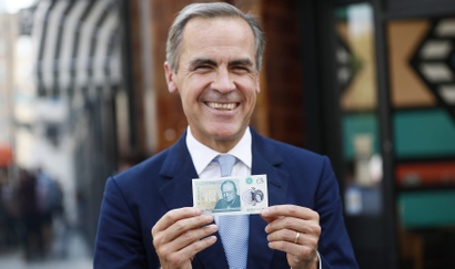Bank of England governor Carney poses with a new polymer five pound note at Whitecross Street Market in London