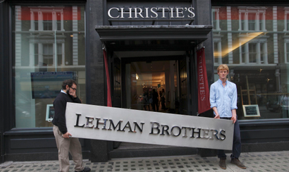 Christie's employees pose for a photograph with a Lehman Brothers sign at Christie's in central London September 24, 2010. Various items are on display before the auction of Lehman Brothers: Artwork and Ephemera, which will take place on September 29. REUTERS/Andrew Winning (BRITAIN - Tags: ENTERTAINMENT BUSINESS SOCIETY) - RTXSLK5