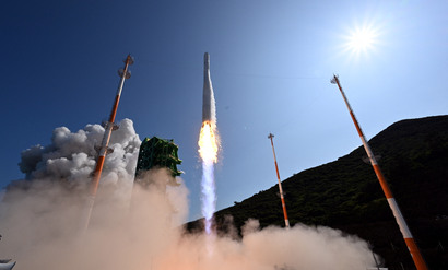 A rocket blasts into the sky from a launch pad.