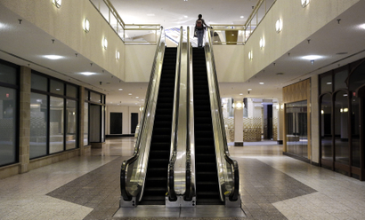 A woman rides an escalator past closed storefronts inside the largely empty White Flint Mall, Monday, Dec. 1, 2014, in Bethesda, Md. Opened in 1977, just two tenants remain as the mall's owner plans to eventually replace it with a mix of housing, office space and outdoor shopping. (AP Photo/Patrick Semansky)