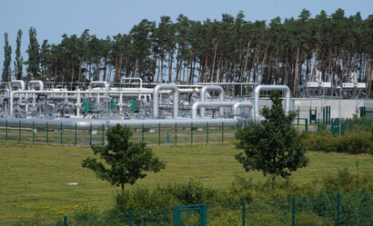 A field with natural gas pipes, backed by trees.