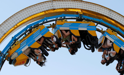 People wearing protective face masks ride a roller coaster as they enjoy the sunny weather at the Brighton Palace Pier