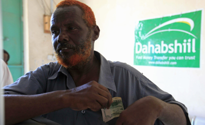 A Somali man withdraws money from a Dahabshiil money transfer office in "Kilometer Five" street of Soobe village, southern Mogadishu, May 8, 2013. Somalia's government must lure more investors to drive the private economy because business owners have an interest in cementing fragile security gains, the chief executive of Somalia's biggest financial firm said.