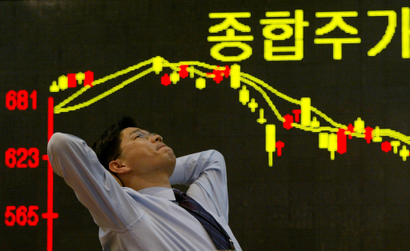 FILE PHOTO: A South Korean employee of a securities firm reacts in front of a graph showing stock price in Seoul March 11, 2003. /File photo - S1AETLECOXAA