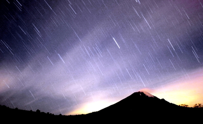 A meteor shower lights up the sky over the Mexican volcano Popocatepetl near the village San Nicolas de los Ranchos in Mexican state of Puebla in the early hours of December 14, 2004. The shower, named Geminid because it appears to originate from the constellation Gemini, lit up the sky with dozens of shooting stars per hour.