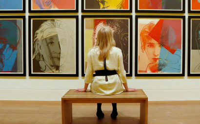 Gallery employee Maddy Adeane poses with Andy Warhol's "Ten Portraits of Jews of the Twentieth Century"
