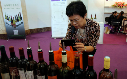 A woman takes pictures of labels of wine at Wine China Expo 2013 in Beijing September 24, 2013. China is the world's fifth-largest wine consumer, according to a study last year for VINEXPO, an annual wine trade show that alternates between Bordeaux and Hong Kong. The study forecast annual consumption growth in China and Hong Kong at 54.3 percent between 2011 and 2015, or a billion more bottles every year. REUTERS/Kim Kyung-Hoon (CHINA - Tags: FOOD BUSINESS SOCIETY) - RTX13XE3