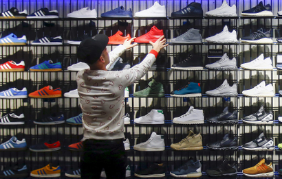 A shop assistant works at the Adidas flagship store in Berlin, Germany, January 20, 2016. A combination of new and retro sneaker styles will keep driving growth at Adidas's fashion business and help attract more sports fans too, the head of the German firm's Originals unit said in an interview. Picture taken January 20, 2016. REUTERS/Hannibal Hanschke - RTX23CBS