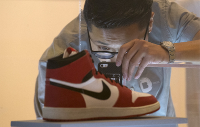 A visitor photographs an Air Jordan I during a preview for "The Rise of the Sneaker Culture" exhibit at the Brooklyn Museum in the Brooklyn borough of New York, July 8, 2015.