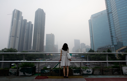 A woman stands on an overhead bridge near the construction site of "Kaisa Plaza", then named "Changan No. 8" (L), on a hazy day in Beijing's central business district in this July 28, 2012 file picture. Struggling Chinese developer Kaisa Group plunged further into crisis on Monday as several of its bank accounts were frozen and a number of creditors sought immediate repayment of debts. REUTERS/Jason Lee/Files (CHINA - Tags: ENVIRONMENT BUSINESS) - GM1EB1D16G601