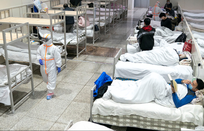 Medical workers in protective suits attend to patients at the Wuhan International Conference and Exhibition Center, which has been converted into a makeshift hospital to receive patients with mild symptoms caused by the novel coronavirus, in Wuhan, Hubei province, China February 5, 2020. Picture taken February 5, 2020. China Daily via REUTERS ATTENTION EDITORS - THIS IMAGE WAS PROVIDED BY A THIRD PARTY. CHINA OUT. - RC2UUE9ADN51