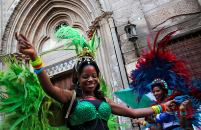 Two Nigerian women in very colorful carnival outfits with headdress dance outside a historic building in Cairo.