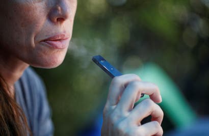 A woman smokes a Juul e-cigarette in this posed picture, near Jerusalem