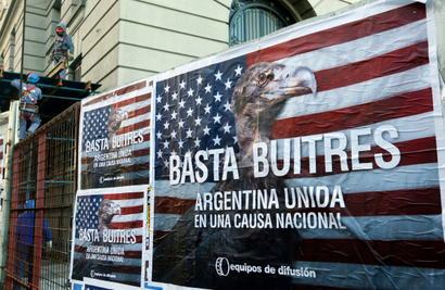 Construction workers work near posters that read "Enough vultures, Argentina united for a national cause" in Buenos Aires June 18, 2014. Argentina is taking steps to place its restructured debt under local law so it can continue making payments despite a string of adverse U.S. court rulings, Economy Minister Axel Kicillof said on Tuesday as fears of default increased. Under the move, Argentina would swap bonds that are governed by U.S. law for those governed by Argentine law, meaning they would no longer be subject to the U.S. courts. REUTERS/Enrique Marcarian (ARGENTINA - Tags: BUSINESS POLITICS CRIME LAW) - RTR3UG0T
